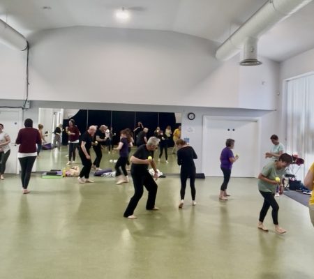 Participants moving around the room with tennis balls during The Playful Reset
